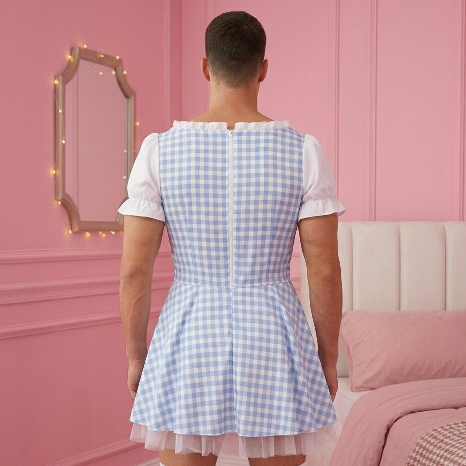 Person wearing a blue checkered dress in a room with pink walls and bedding.