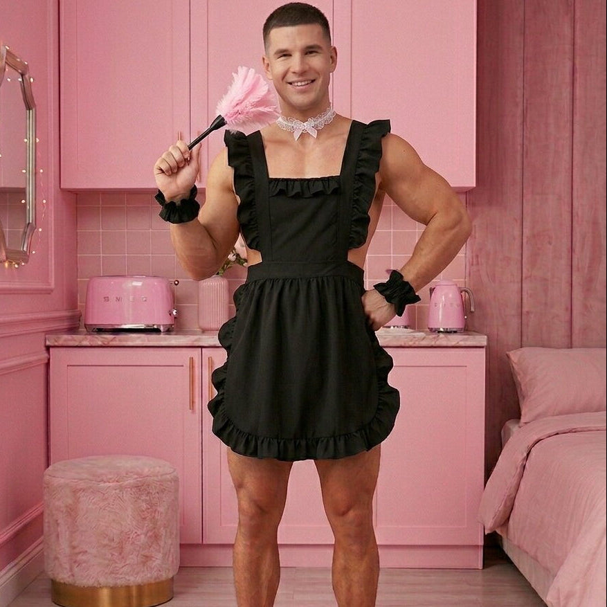 Man in a black dress posing in a pink room