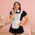 Man wearing a black and white maid outfit in a bedroom setting