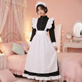 Woman wearing a black and white maid outfit in a bedroom setting with pink walls and decor.
