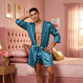 Man in a blue satin robe standing in a bedroom with pink walls and furniture.