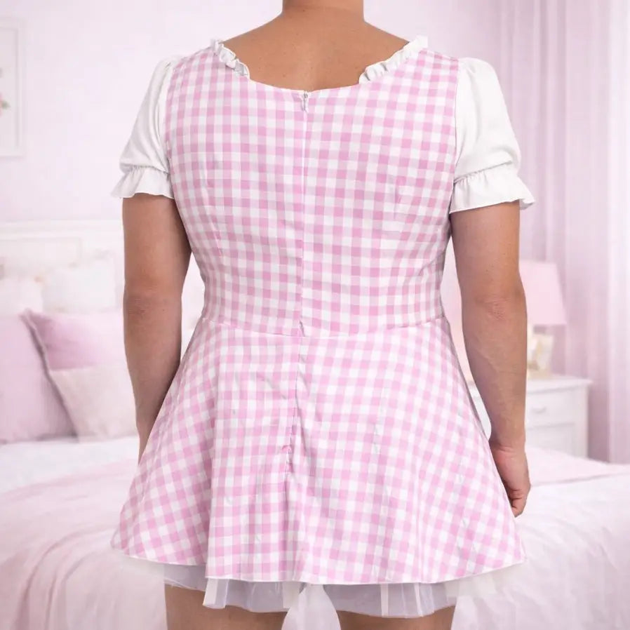 Man wearing a pink and white checkered dress in a bedroom setting