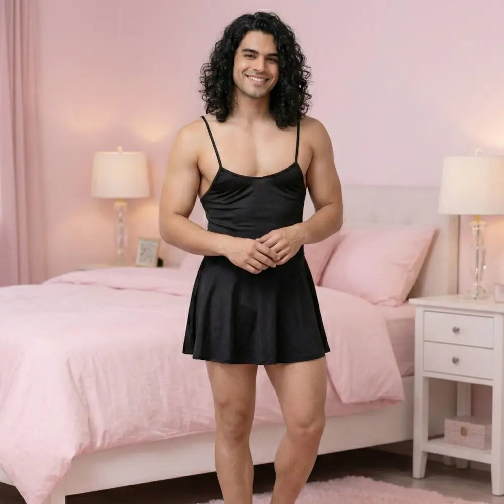 Man wearing a black satin nightgown in a bedroom with pink bedding and decor.