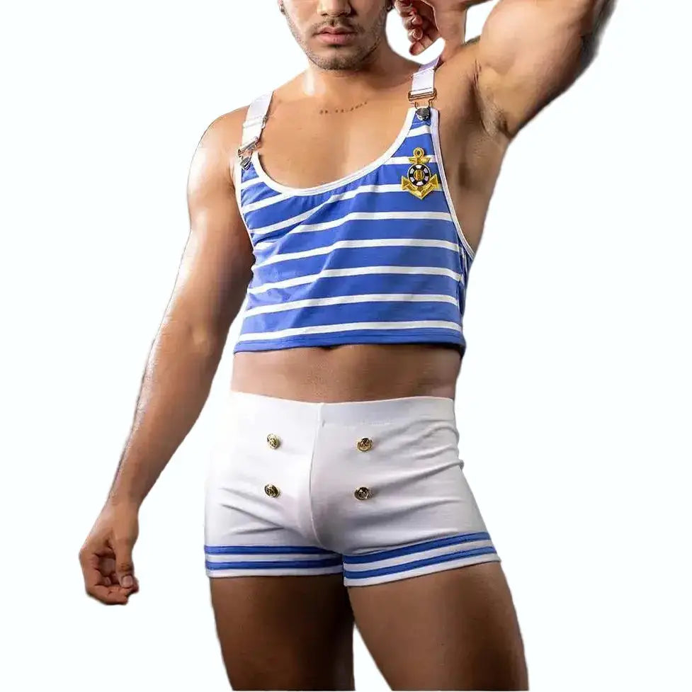 Man wearing a blue and white striped tank top and white shorts with a captain's hat on a dark background