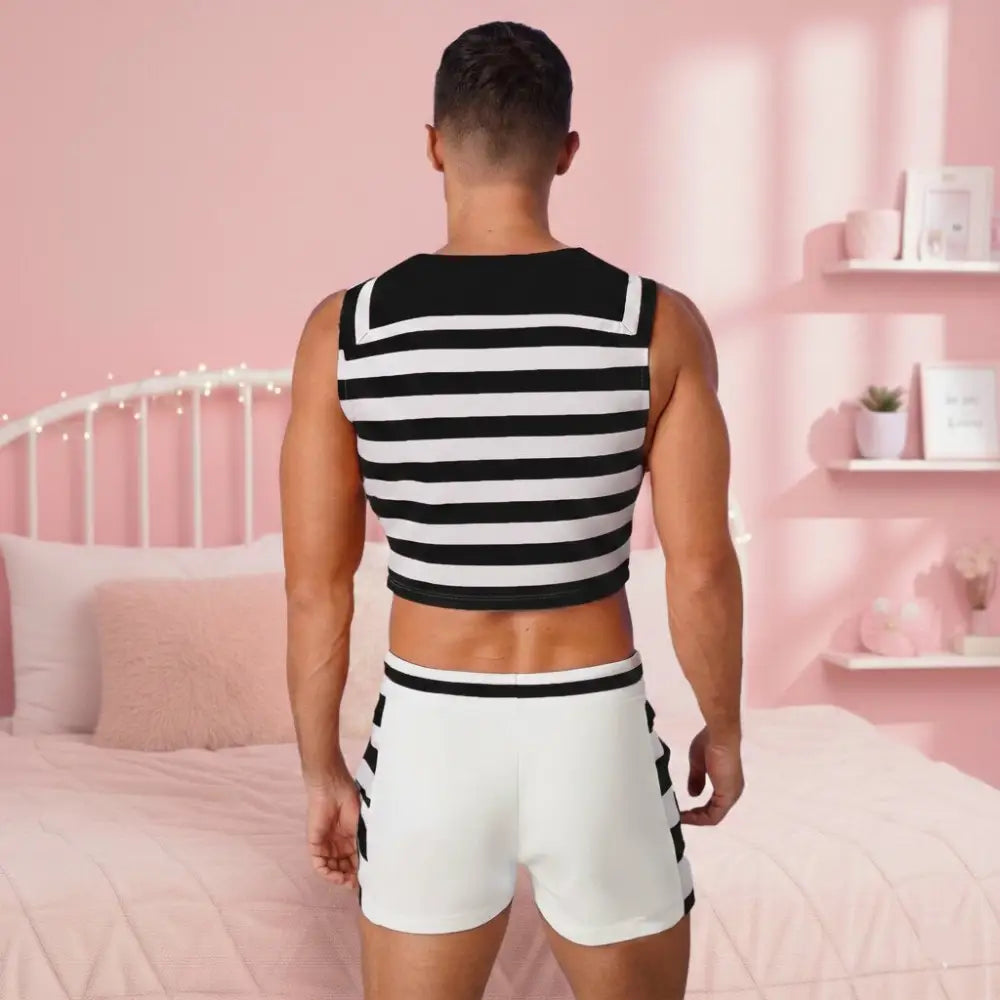 Man wearing a black and white striped tank top and shorts in a bedroom setting.