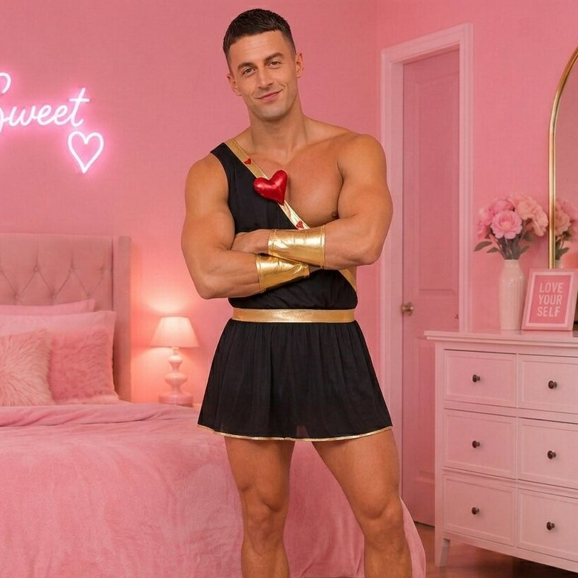 Man in a black outfit with gold arm bands standing in a pink bedroom.